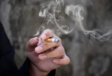Mão segurando um cigarro aceso