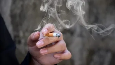 Mão segurando um cigarro aceso