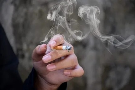 Mão segurando um cigarro aceso