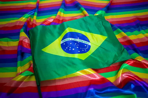 Urna eletrônica e bandeira com as cores do arco-íris representando candidaturas LGBT+